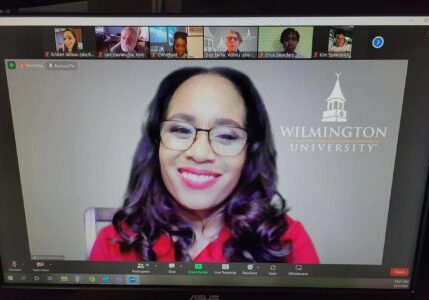 A woman with glasses is on the screen of her computer.