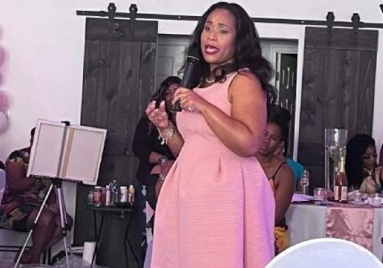 A woman in pink dress holding onto a microphone.