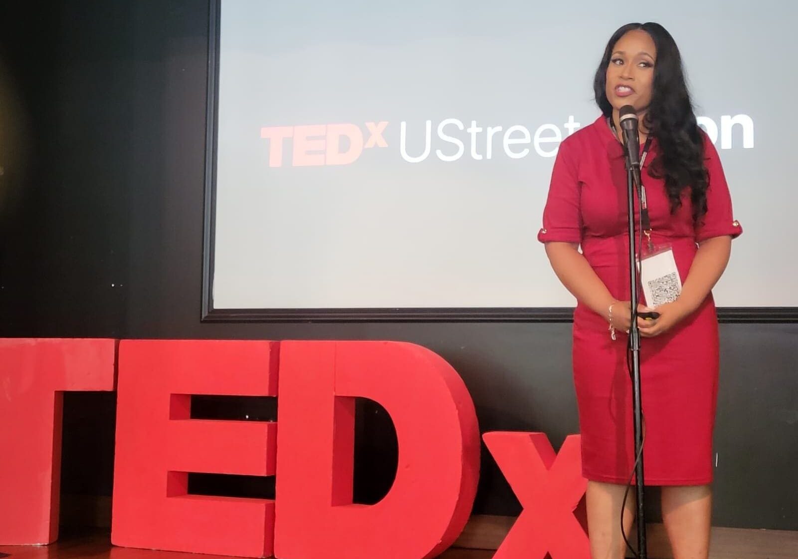 A woman standing in front of a tedx sign.